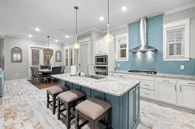 a kitchen with white cabinets and a island with bar stools at Endless Summer in Inlet Beach
