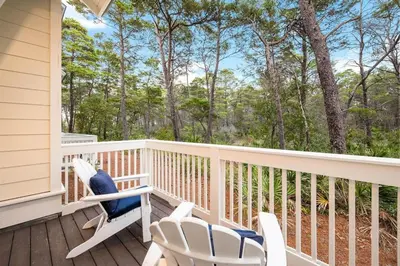 a porch with chairs and trees in the background at Endless Summer in Inlet Beach