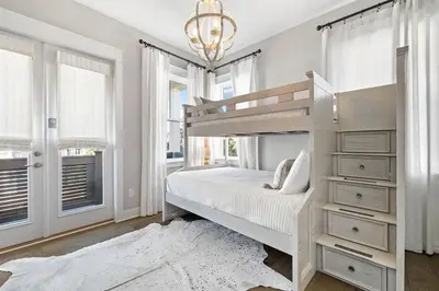 a white bedroom with a bunk bed and a chandelier at The Tipsy Turtle in Inlet Beach