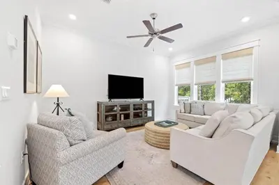 a living room with two white chairs and a flat screen tv at Suits Us in Inlet Beach