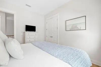 a white bedroom with a bed and a tv at Suits Us in Inlet Beach