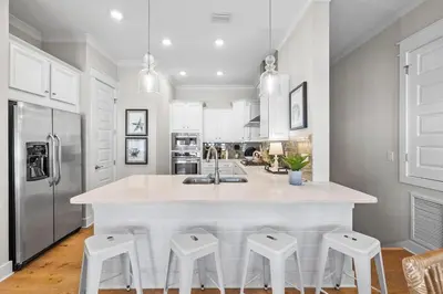a kitchen with white cabinets and a large island with stools at Lovely Day on 30A in Inlet Beach