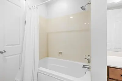 a white bathroom with a tub and a shower at The Alexander in Seacrest