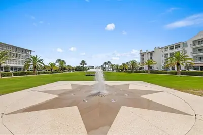 a fountain in a park with palm trees and buildings at The Alexander in Seacrest