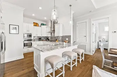 a white kitchen with a large island with bar stools at Sea Ya Soon in Inlet Beach