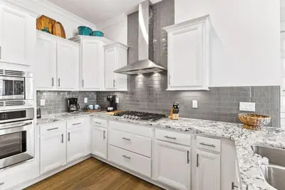 a white kitchen with white cabinets and marble counter tops at Sea Ya Soon in Inlet Beach