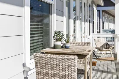 a wooden table on a porch with two potted plants at White Sand Dreamin' in Inlet Beach