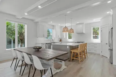 a white kitchen with a wooden table and chairs at Dune Drifter in Seagrove Beach