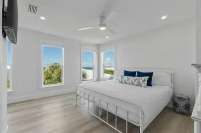 a white bedroom with a bed and two windows at Dune Drifter in Seagrove Beach