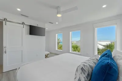 a white bedroom with a bed and two windows at Dune Drifter in Seagrove Beach