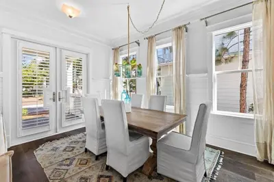 a dining room with a wooden table and white chairs at It's a Shore Thing in Inlet Beach