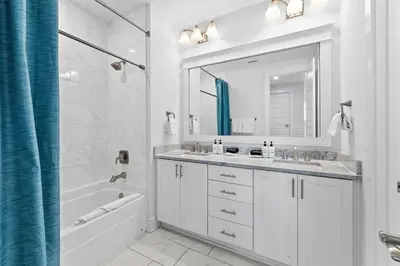 a white bathroom with a tub and a sink and a mirror at It's a Shore Thing in Inlet Beach