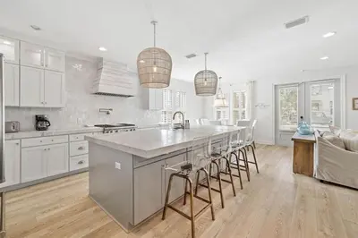 a kitchen with white cabinets and a large island with bar stools at A Lovely Stay on 30A in Seacrest