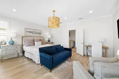 a bedroom with a bed and a blue chair at A Lovely Stay on 30A in Seacrest