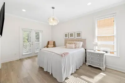 a white bedroom with a bed and a chandelier at A Lovely Stay on 30A in Seacrest