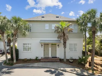 a white house with palm trees in front of it at Resting Beach Place in Inlet Beach