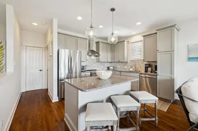 a kitchen with white cabinets and a island with stools at Resting Beach Place in Inlet Beach
