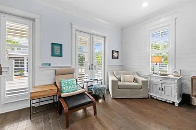 a living room with a chair and a couch and windows at Sol Mates in Inlet Beach
