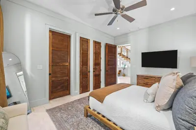 a bedroom with a bed and a flat screen tv at Sadie's Cottage in Rosemary Beach