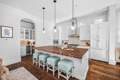 a kitchen with white cabinets and a large island with blue chairs at Sadie's Cottage in Rosemary Beach
