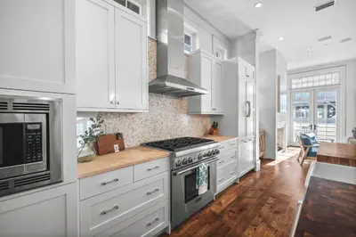 a kitchen with white cabinets and a stove top oven at Sadie's Cottage in Rosemary Beach