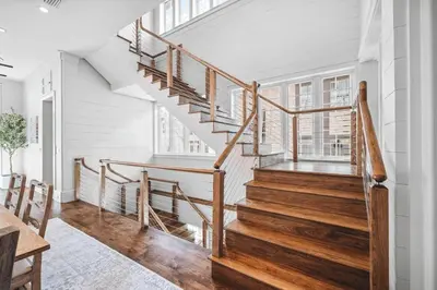 a staircase in a home with white walls and wooden floors at Sadie's Cottage in Rosemary Beach