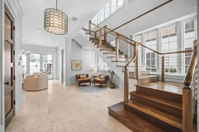 a hallway with a staircase and a living room at Sadie's Cottage in Rosemary Beach
