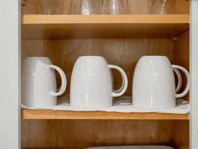 three white coffee mugs sitting on a shelf at Sweet Bay on 30A in Seagrove Beach