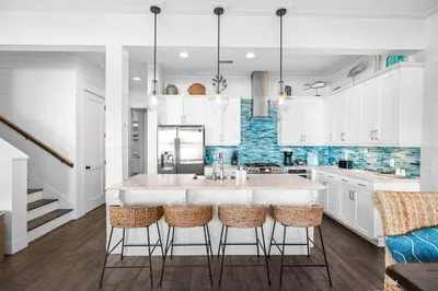 a kitchen with white cabinets and a large island with bar stools at Southern Comfort in Seacrest