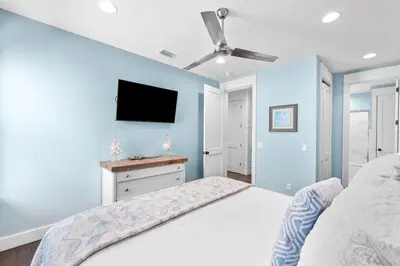 a bedroom with blue walls and a bed with a ceiling fan at Southern Comfort in Seacrest