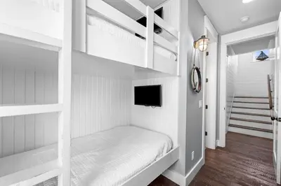 a bedroom with white bunk beds and a tv at Southern Comfort in Seacrest