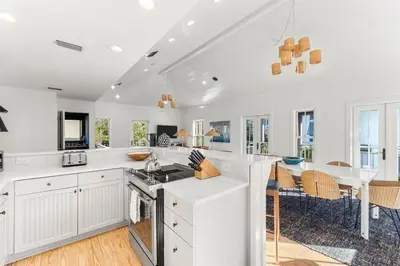 a kitchen with white cabinets and a dining room with a table at The Last Waltz in Seacrest