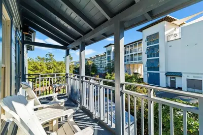 a balcony with white chairs and a building at The Last Waltz in Seacrest
