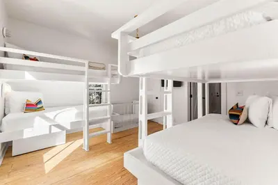 a white bedroom with two bunk beds and a couch at The Last Waltz in Seacrest