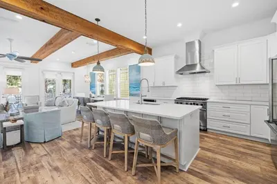 a kitchen with white cabinets and a large island with chairs at Villa Bianca in Seacrest