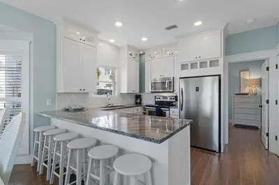 a kitchen with white cabinets and bar stools at Seahorse Landing in Seagrove Beach