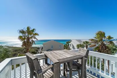 a wooden table on a balcony with the beach at Seahorse Landing in Seagrove Beach