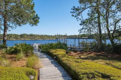 a wooden pathway next to a lake with trees at Casa de Sol in Inlet Beach
