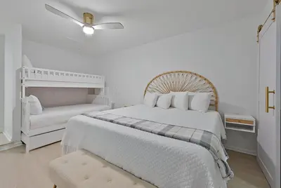 a white bedroom with a large bed and a chair at Gulfs Edge Townhome #7- Sun-Kissed Memories by Emerald Coast Retreats in Panama City Beach
