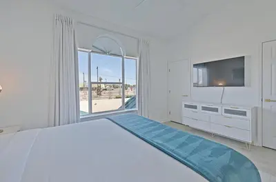 a white bedroom with a large bed and a flat screen tv at Gulfs Edge Townhome #7- Sun-Kissed Memories by Emerald Coast Retreats in Panama City Beach