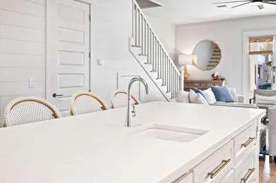 a white kitchen with a sink and a living room at Sweet Southern Charm in Seacrest