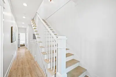 a white staircase in a home with wood floors at Sweet Southern Charm in Seacrest