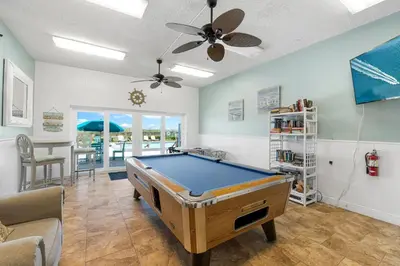 a pool table in a living room with a ceiling fan at Mariner West #403 in Panama City Beach