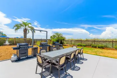 a picnic table and chairs with a grill and a barbecue at Mariner West #403 in Panama City Beach