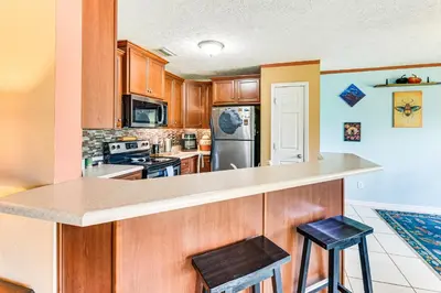 a kitchen with wooden cabinets and a counter with stools at 2 Mi to Beach and Boating Family Home in Lynn Haven in Lynn Haven