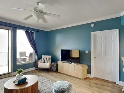 a living room with blue walls and a flat screen tv at Treasure Island #1707 in Panama City Beach