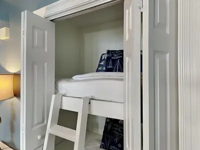 a white bunk bed in a small room with a ladder at Treasure Island #1707 in Panama City Beach