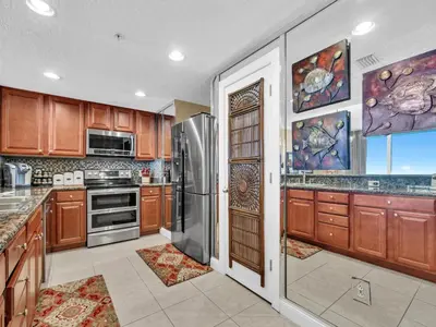 a kitchen with wooden cabinets and a stainless steel refrigerator at Palazzo 1405 by Emerald Coast Retreats in Panama City Beach