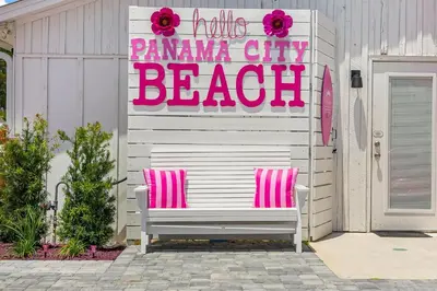 a bench with a hello pamana city beach sign on a house at Pink Prerogative Beach Bungalow with Private Pool in Panama City Beach