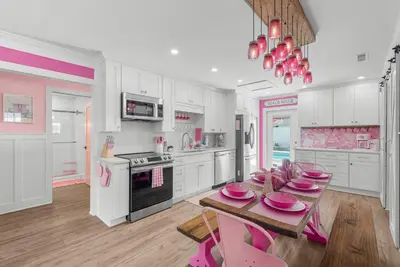 a kitchen with a table with pink plates on it at Pink Prerogative Beach Bungalow with Private Pool in Panama City Beach
